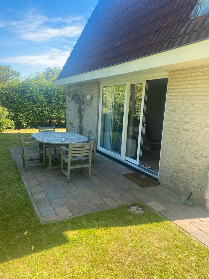 Terrasse mit rundem Tisch, Stühlen und Schiebetür